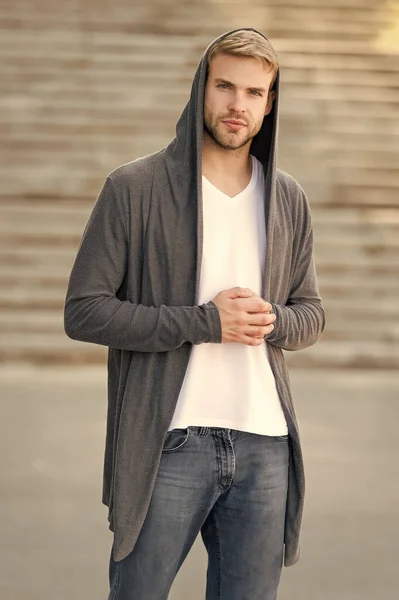 Comfortable clothes daily wear. Great taste to dress well. Male fashion influencer. Fashionable young model man. Street style outfit. Handsome man with hood standing urban background. Fashion trend