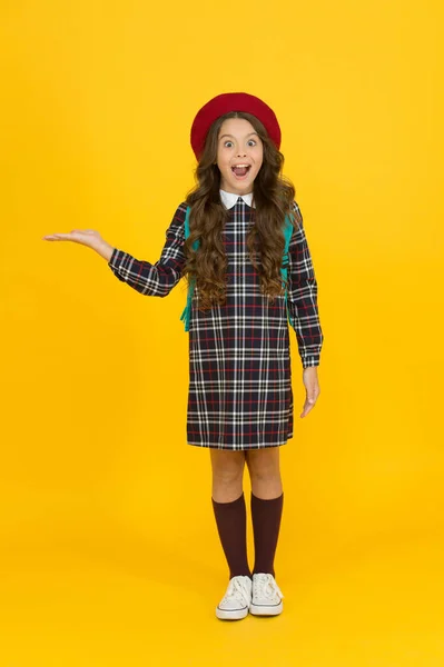 Menina surpreso em uniforme escolar, apresentando produto — Fotografia de Stock