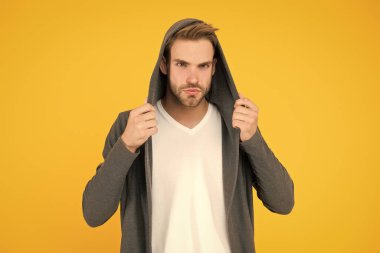 Esneme malzemesi. Yakışıklı adam kapüşonlu şık bir manto giyiyor. Sıradan erkek giyimi. Moda trendleri. Gençler için modern kıyafetler. Günlük yaşam için rahat kıyafetler. Moda adamı sarı arka plan. Moda bakışı.