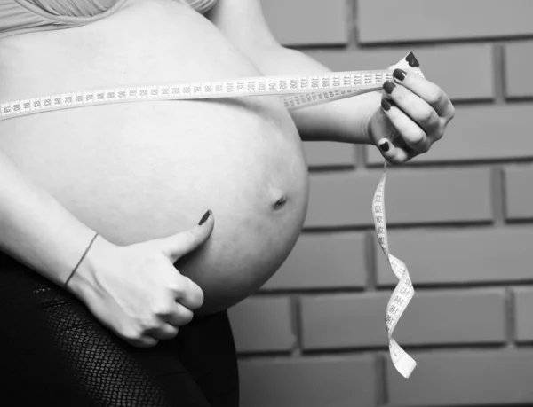 Vrouw buik van zwanger naakt vrouw in zwart vacht — Stockfoto