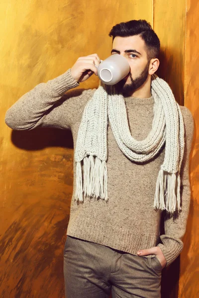 bearded man drinking tea, coffee from cup with serious face