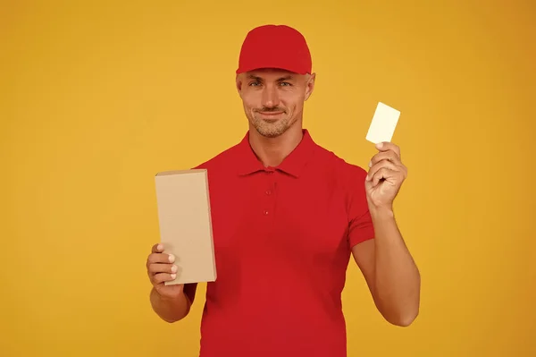 仕事の連絡先。無料の割引カードを入手します。目的地までお届けします。配送サービス。宅配便と配達。郵便配達員だ。ハンサムな男の赤い帽子黄色の背景。購入する — ストック写真