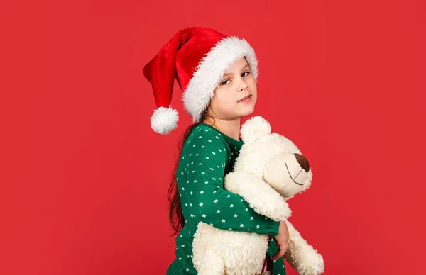 Oso polar. Comprando regalos de Navidad. Vacaciones de Navidad. Temporada alegre de invierno. Venta de compras de Navidad. Pequeño Santa con juguete. Niña Santa Claus sombrero fondo rojo. Osito de peluche. Vibras navideñas —  Fotos de Stock