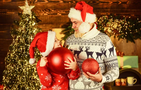 Familie versieren huis en kerstboom. Kerstvakantie in de winter. Gelukkig nieuwjaar. Een bebaarde vader en een kleine meisjes kerstmuts. grappige gebreide trui. Vader en dochter vieren kerst. Kerstmis feest samen — Stockfoto