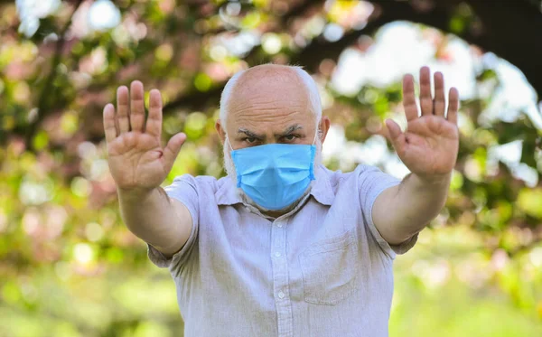 Ga niet naar buiten. let op de voorzorgsmaatregelen tijdens de pandemie. gezond leven. dragen masker in bloeiende roze sakura park. Een man met een beschermend masker. geur bloeiende bloemen op coronavirus quarantaine — Stockfoto