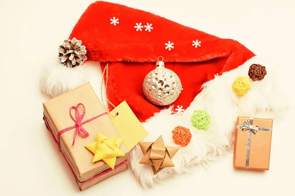 Atributos de vacaciones de invierno. Sombrero de Santa y caja de regalo de Navidad. Regalos de Navidad de Santa. Santa sombrero blanco vista superior de fondo. La atmósfera se trata de detalles. Año nuevo y el estado de ánimo festivo de Navidad — Foto de Stock