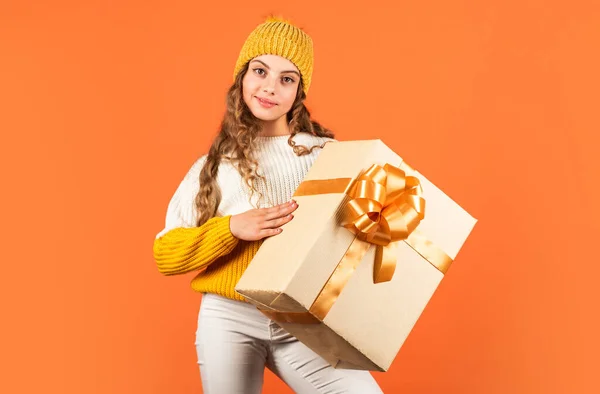 Lo que hay dentro. sorpresa de vacaciones de invierno. niña pequeña de punto sombrero y suéter. niño mantenga presente caja fondo naranja. feliz año nuevo 2020. servicio de entrega de regalos. ventajas de compra. Navidad está aquí. — Foto de Stock