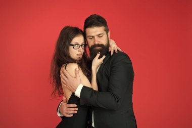 Mükemmel bir çift. Kırmızı arka planda aşık bir çift. Bir çift şehvetli kadın ve sakallı adam. Sevgili çift resmi kıyafetle sarılıyor. Evlilik yıldönümü. Tatil kutlaması. Sevgililer Günü. Romantizm. Aşk