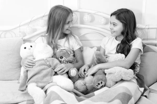 Soulmates concept. Sisters sharing toys. Sisters best friends. Kids play toys in bed. Little girls spend time together. Friendship personal relations. Toys shop. Cute soft toys. Happy childhood