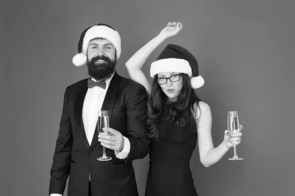 Couple in love at party. Winter party. Cheerful people. Merry christmas. Office party. Happy new year. Bearded man in tuxedo and girl elegant dress drinking sparkling wine and dancing red background