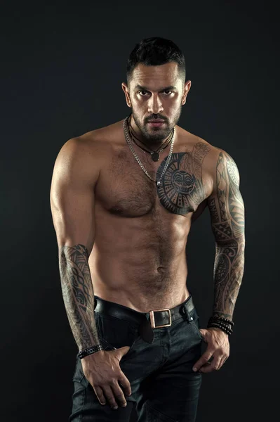 Tempting glance. Bearded man with tattooed torso. Macho sexy bare torso. Fit model with tattoo art on skin. Sportsman or athlete with beard and hair. Sport and fitness. Masculinity. Muscular torso