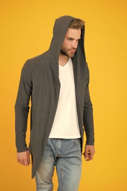 Günlük yaşam için rahat kıyafetler. Moda adamı sarı arka plan. Moda bakışı. Yakışıklı adam kapüşonlu şık bir manto giyiyor. Erkekler için günlük kıyafet. Moda trendleri. Gençler için modern kıyafetler. Spor tarzı.