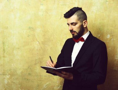 Özenli görünümlü sakallı ofis müdürü deftere planlar yazar.