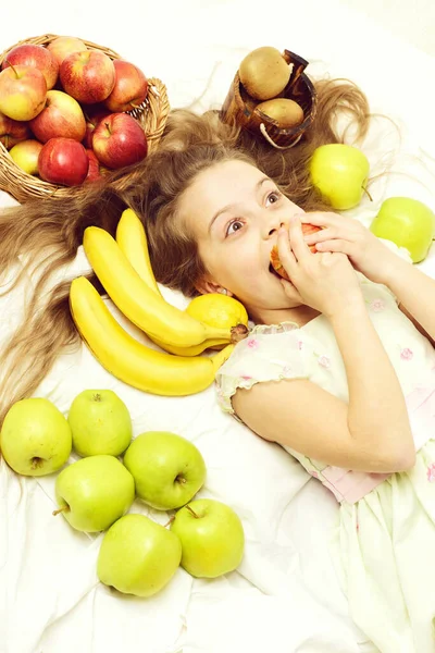 Kind, süßes Mädchen, das mit bunten Früchten im Korb liegt — Stockfoto