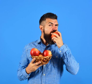 Sakallı adam elinde meyve dolu hasır kasesi tutuyor.