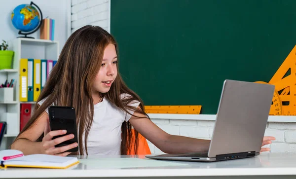 Bambino in classe scuola con computer e telefono cellulare, educazione online — Foto Stock