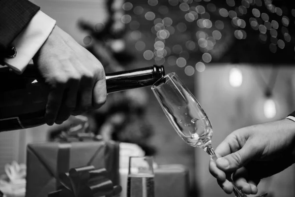 Mani versando champagne in eleganti decorazioni natalizie in vetro sfondo. All'ultimo minuto prima del nuovo anno. Bevi champagne o spumante. Festeggia la festa con lo champagne. Felice anno nuovo — Foto Stock