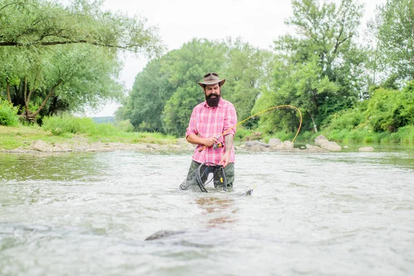 La vita e 'bella. hobby e attività sportive. pescatore mostrano tecnica di pesca uso canna. uomo maturo pesca a mosca. uomo cattura il pesce. Buon pescatore barbuto in acqua. weekend estivo. Pesca a mosca — Foto Stock