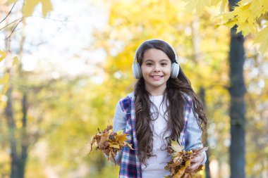 Tamamen özgür hissediyorum. Mutlu çocuk kulaklık takıyor. Genç kız okula giderken müzik dinler. Çocuk sonbahar ormanında yürüyor. Akçaağaç yaprakları dökülüyor. Online eğitim. çocukluk mutluluğu. Güzellik ve doğa