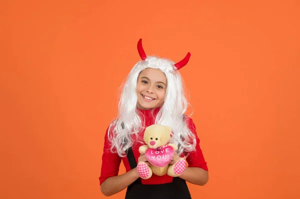 Щаслива дитина носить диявольські роги, тримаючи плюшевий ведмідь іграшковий подарунок на Хелловін, щасливі подарунки на Хелловін — стокове фото