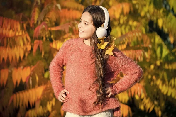 Jesienne spacery z ładnymi piosenkami. Słuchanie audio w najlepszy sposób pomaga dziecku poprawić słownictwo. Kid girl relaks w pobliżu jesiennego drzewa ze słuchawkami. Muzyka na jesienny nastrój. Słuchanie piosenki. Ciesz się muzyką jesienią — Zdjęcie stockowe