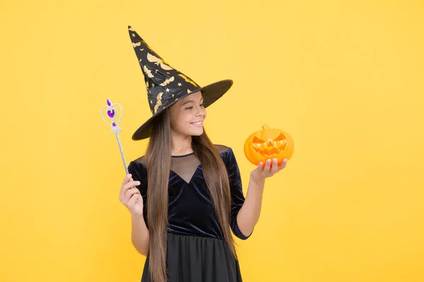 Gyermekkori őszi nyaralás. tini lány készen áll az ünneplésre. jelmezes buli. Boldog Halloweent! Boszorkánykalapos gyerek. A kölyök varázspálcát és sütőtököt tart. Boszorkányság és varázslat. Üdv a Rémálomban. — Stock Fotó