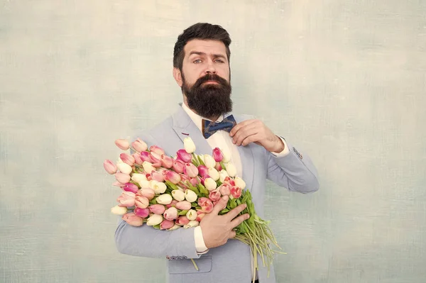 Joyeuse journée des femmes. L'homme barbu tient des fleurs printanières. Bouquet de tulipes pour la journée des femmes. Hipster porter costume formel et noeud papillon. Prêt pour la célébration de la journée des femmes. 8 mars. Fête internationale des femmes — Photo