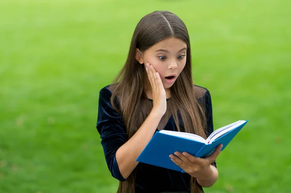 La sorpresa ayuda a estudiar cosas nuevas. Niño sorprendido leer libro de estudio al aire libre. Conocimiento e información. Biblioteca escolar. Lectura de educación. Motivación e interés. Atraer la atención de los alumnos — Foto de Stock