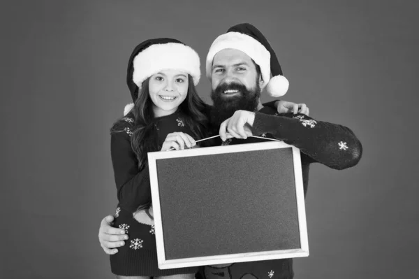 Festeggia Natale e Capodanno con Babbo Natale. La famiglia felice tiene la lavagna vuota. Padre e figlia con Babbo Natale sembrano sfondo rosso. Babbo Natale. Unisciti a noi per Babbo Natale, copia lo spazio — Foto Stock