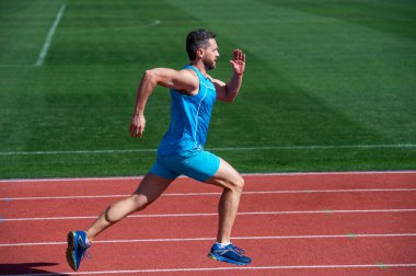 Büyük ilerleme. Kaslı adam başarıya koşar. Stadyumda koşan bir adam. Spor, sağlıklı yaşam tarzı rutini. Spor antrenmanı. Erkek sporcu sabah egzersizi yapar. Sporcu koşucu dışarıda. Sağlık hizmeti. enerji