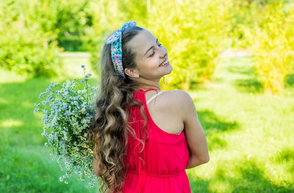 Feliz niña sonrisa con ramo de flores en el soleado paisaje de verano al aire libre, cumpleaños —  Fotos de Stock