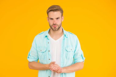 Kendine güveni olan bir adam, sarı arka plan, özgüven ve karizma üzerine kot giyer.