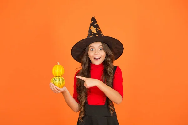 Teenage girl in witch hat celebrate halloween. happy halloween. trick or treat concept. carnival festive costume of witch. kid pointing finger on small pumpkin. child celebrate autumn holiday — Stock Photo, Image