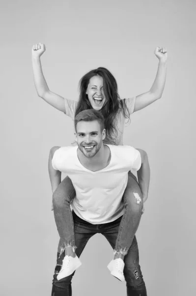 Σταθερή υποστήριξη. Χαρούμενος άντρας που πηδάει την κοπέλα του. Hipster δίνοντας σέξι γυναίκα piggyback βόλτα. Ευτυχισμένο ζευγάρι ερωτευμένο σε κίτρινο φόντο. Λατρεύω το χαμόγελο του ζευγαριού που διασκεδάζει. Απλή ευτυχία — Φωτογραφία Αρχείου
