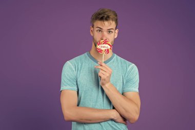 Lolipoplu bir adamın portresi. Aşk ve romantizm. Sevgililer Günü lolipopu olan seksi romantik adam. Adam şeker emiyor. Sevgililer günün kutlu olsun. Dişlerin için sağlıksız. Komik adam lolipop yalıyor