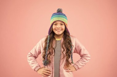 İyi eğlenceler. Küçük kız kış şapkası. Soğuk mevsim için sıcak kıyafetler. Neşeli çocuk pembe arka planı. Çocuk modası ve alışveriş. Moda kızı gülümsüyor. Kış aktivitesi için hazır. Sonbahar tarzı. Mutlu çocukluk