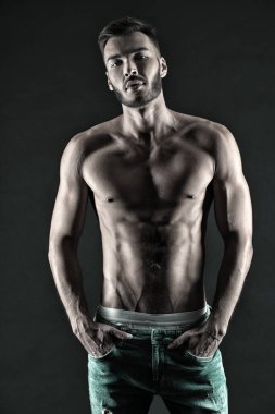 Erkeklik seksidir. Kas kasları gergin kaslar elleri kot pantolonun içine sokar. Maço kaslı göğüs çekici siyah arkaplan gibi görünüyor. Kendine güveni olan kaslı vücutlu bir sporcu