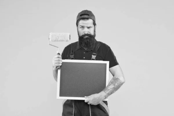 Schilderen werkt. Baard schilder houdt schoolbord vast. Wandschilder met schilderstool. Penseel roller schilder. Bouw en renovatie. Decoratie en inrichting. Zijn diensten promoten. Werkloosheid — Stockfoto