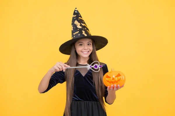 Enfant d'Halloween en chapeau de sorcière tenir baguette magique et citrouille Jack o lanterne pour la sorcellerie, enchantement d'Halloween — Photo