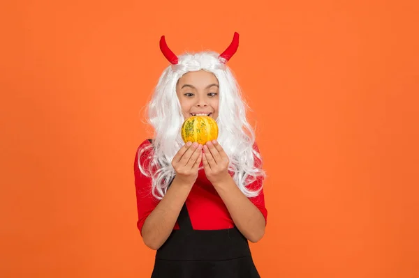 Gelukkig meisje op Halloween dragen grappig carnaval kostuum en duivel hoorns indoor holding pompoen, halloween magie — Stockfoto