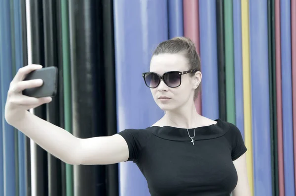 Kobieta robi selfie ze smartfonem w Paryżu, we Francji. Kobieta z telefonem komórkowym na kolorowym tle. Dziewczyna w okularach przeciwsłonecznych z modą i zmysłowym pięknem. Nowa technologia i nowoczesne życie — Zdjęcie stockowe