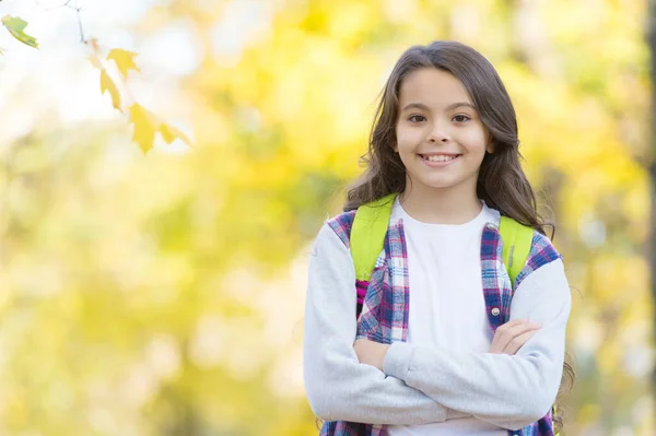 Genç kız okula giderken sırt çantası taşıyor. Çocuk sonbahar ormanında yürüyor. Parkta sonbahar yaprakları. Mevsimsel hava. çocukluk mutluluğu. Güzellik ve doğa. Mutlu çocuk sıradan giyinir. Boşluğu kopyala — Stok fotoğraf