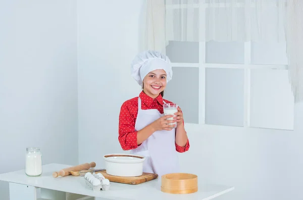 Стакан молока. счастливый ребенок готовит на кухне. испечь печенье на кухне. профессиональный и квалифицированный пекарь. парень в форме шеф-повара и шляпе. девочка-подросток готовит тесто. приготовление торта по рецепту. Время есть — стоковое фото