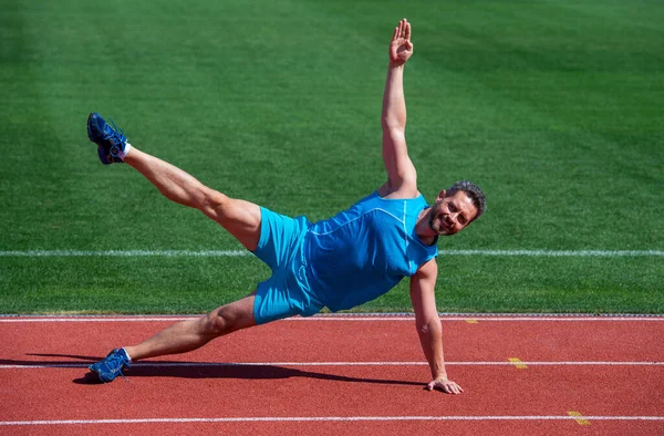 Muskularny mężczyzna stoję w bocznej desce rozciągając się na treningu sportowym, pilates — Zdjęcie stockowe