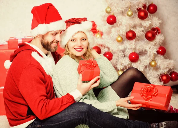 Pareja enamorada disfruta de la celebración navideña. Familia preparó regalos de Navidad. pareja cariñosa abrazo sonriente mientras desembalaje regalos con fondo de árbol de Navidad. La Navidad es tiempo de dar — Foto de Stock