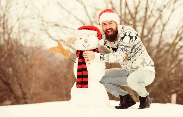 Juegos de invierno. Hipster con barba al aire libre. Hombre con sombrero de Santa Divirtiéndose al aire libre. Chico feliz cara nieve naturaleza fondo. Actividad invernal. Diversión y entretenimiento. Vacaciones de invierno. Hombre de nieve hecho por hombre — Foto de Stock