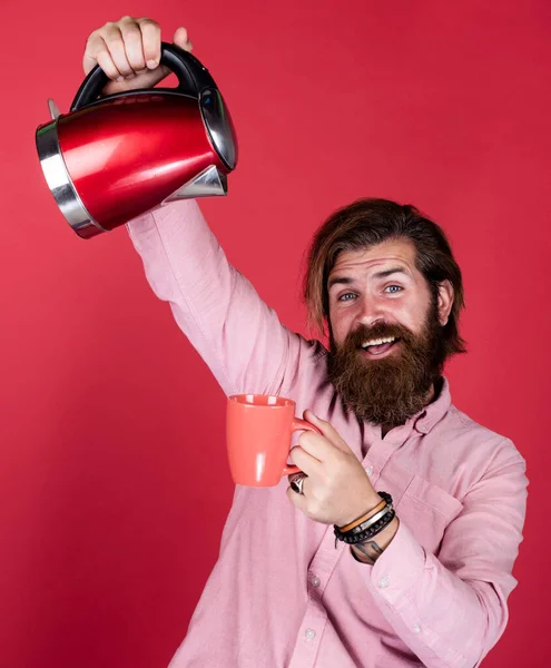 Buvons un coup. J'ai besoin d'eau chaude. homme va boire du thé ou du café. homme brutal avec moustache et barbe. appareil électroménager. homme barbu utiliser bouilloire électrique rouge. concept de ménage masculin — Photo