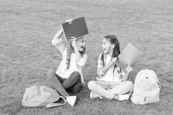 Baw się dobrze. mali przyjaciele zrelaksować się na trawie. Z powrotem do szkoły. literatura dla dziewczyn. razem odrabiać lekcje. Znajdź coś ciekawego w książce. Robię notatki. spędzać wolny czas po szkole — Zdjęcie stockowe