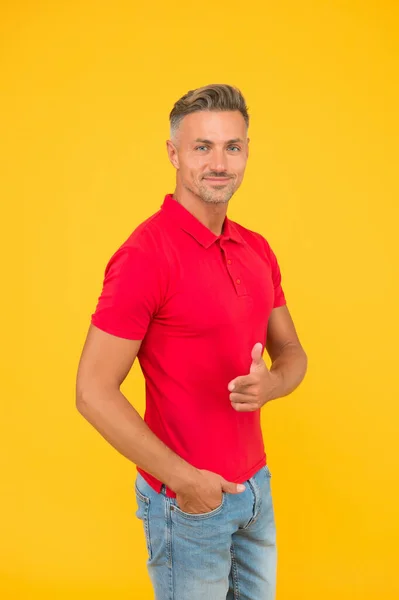 Homme heureux avec des cheveux de barbe élégants dans un style de mode décontracté pointant pistolet main geste fond jaune, publicité — Photo