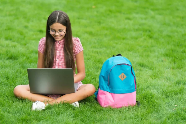 Smart leende tonåring flicka tittar på bärbar skärm med uttryck för spänning och anteckningar, kommunikation i affärsidé — Stockfoto